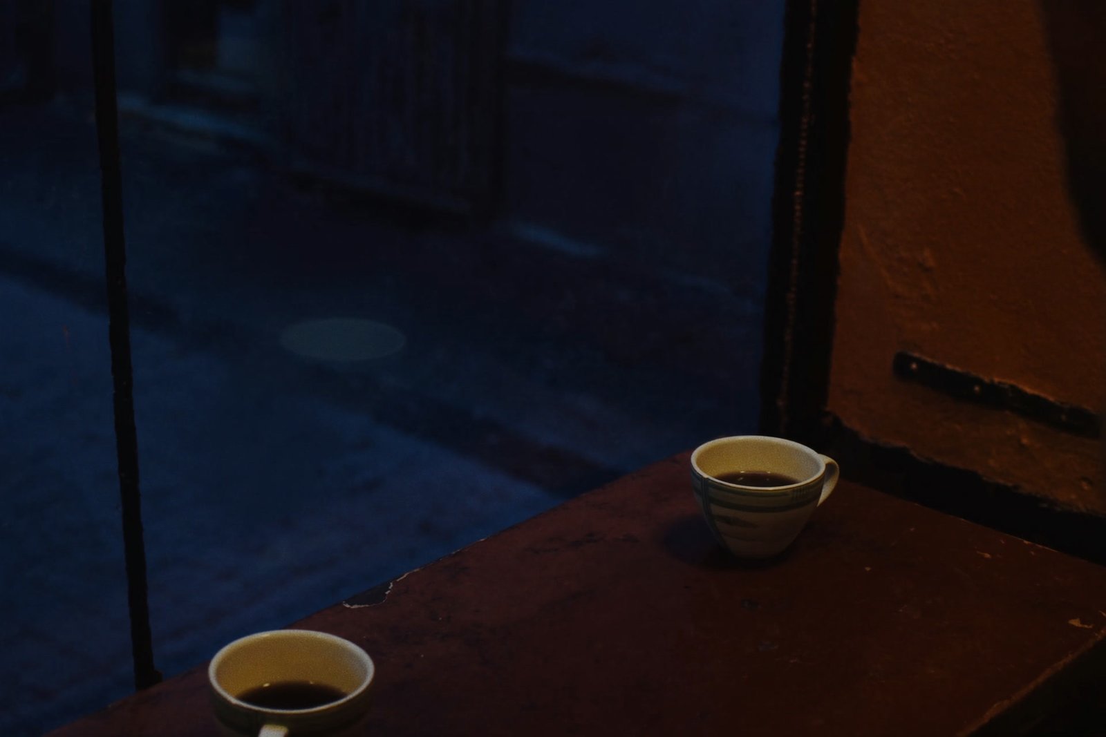 Två kaffekoppar vid ett fönster i skymningen